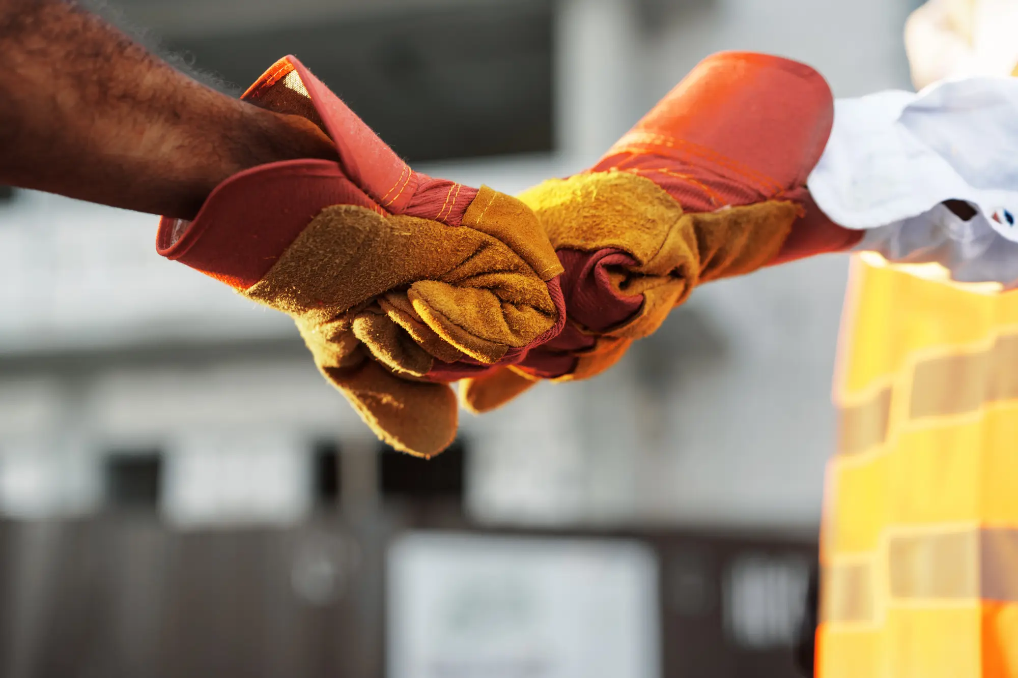 Two workers in gloves shaking hands on a job site