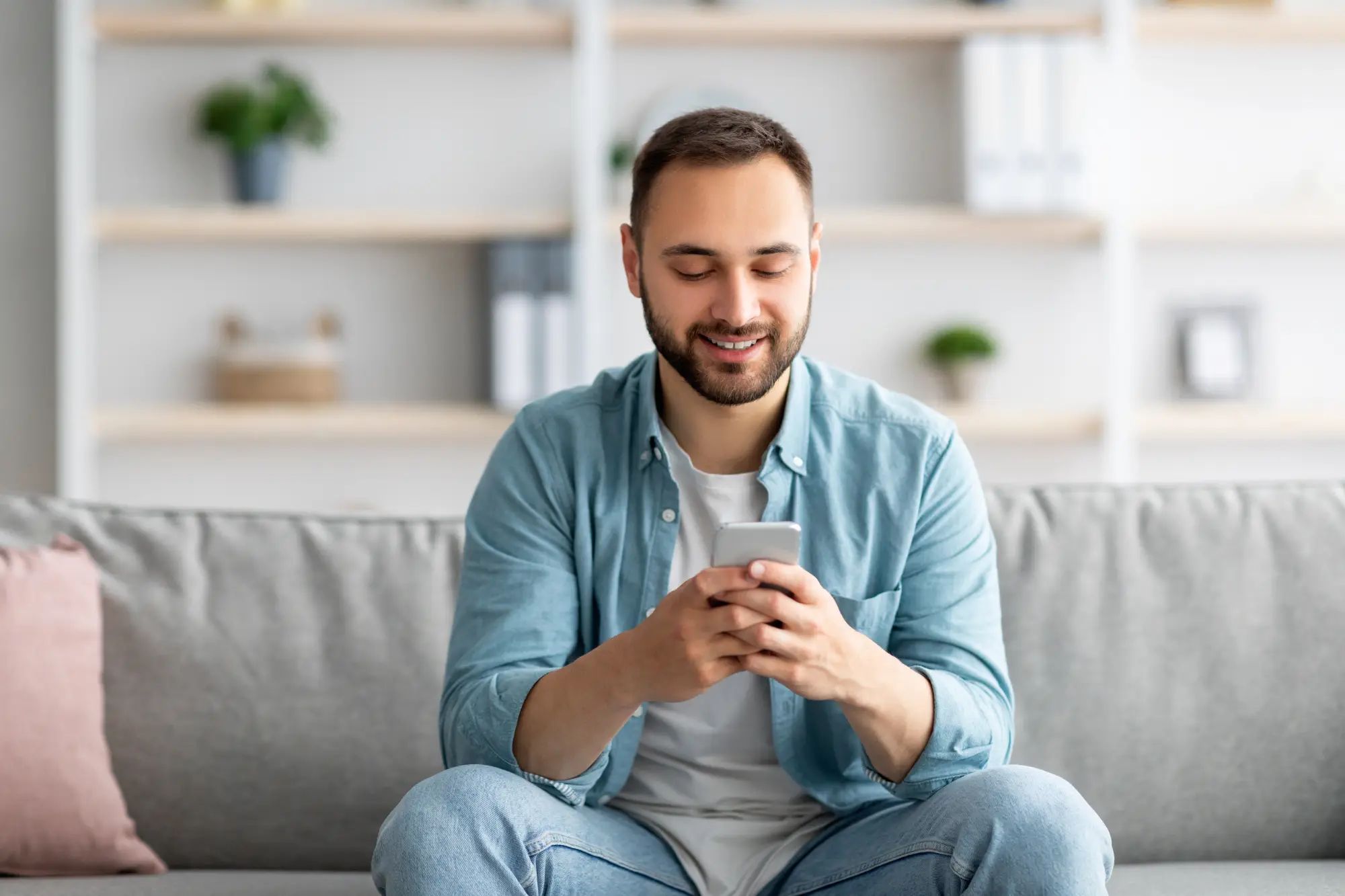 Man sitting on a couch looking at his smartphone