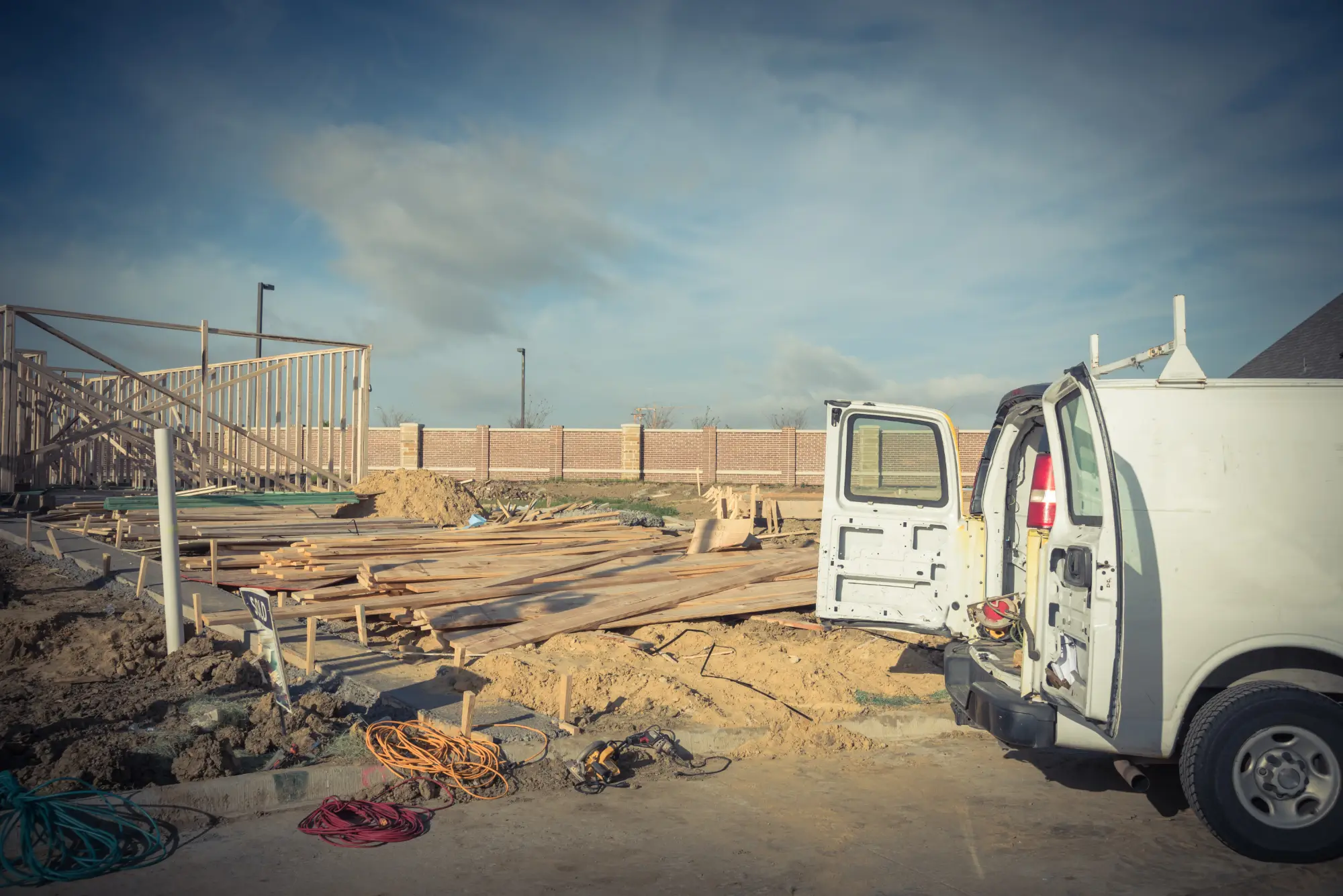 Work van with its rear doors open beside a residential construction site